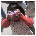 Child holding colured balls to face as eyes